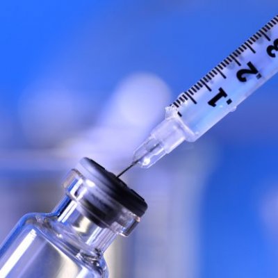 Needle and syringe drawing up clear solution from small vial. Adobe